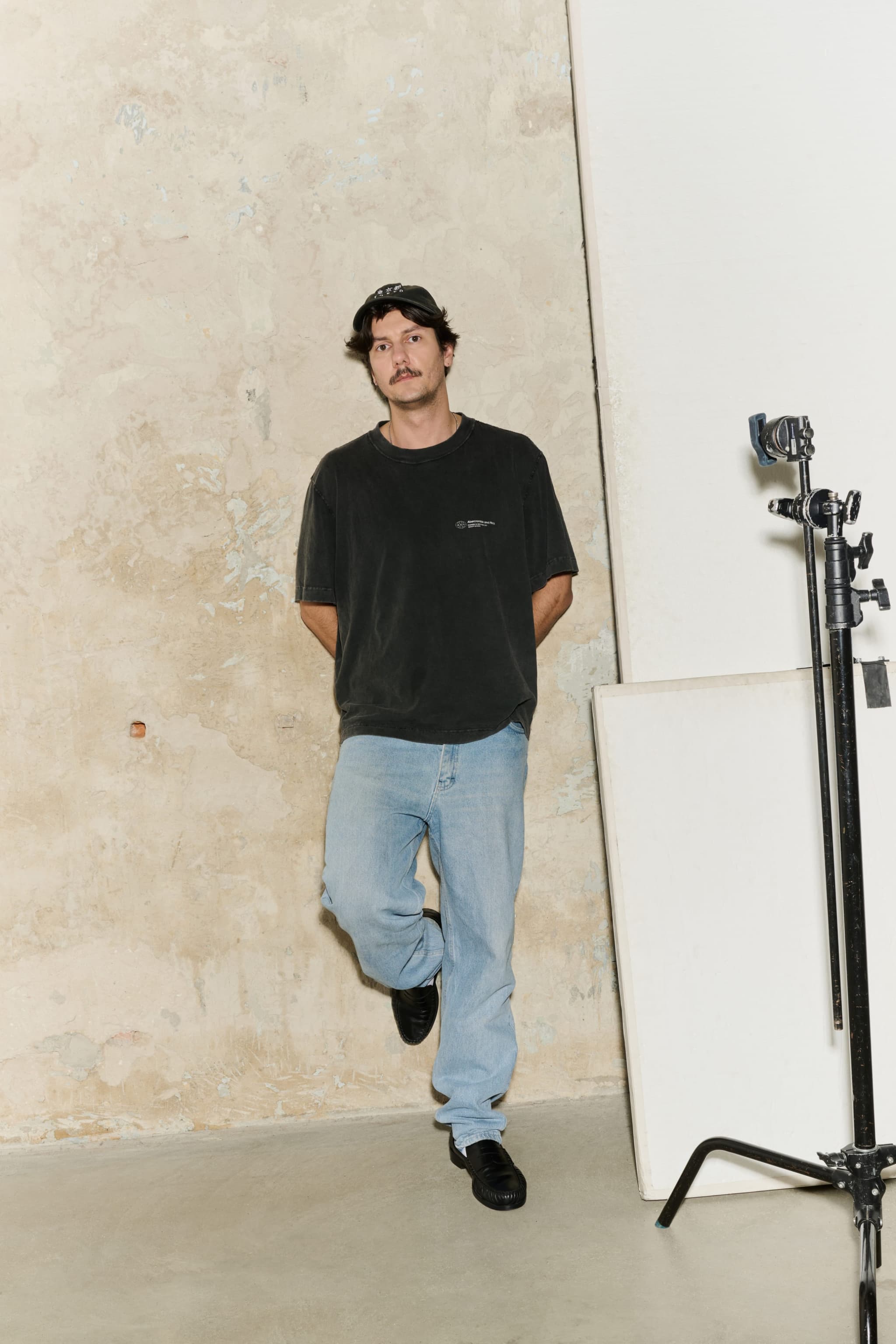 Portrait of Rafał Gruszkiewicz in a black t-shirt and cap in a photo studio.