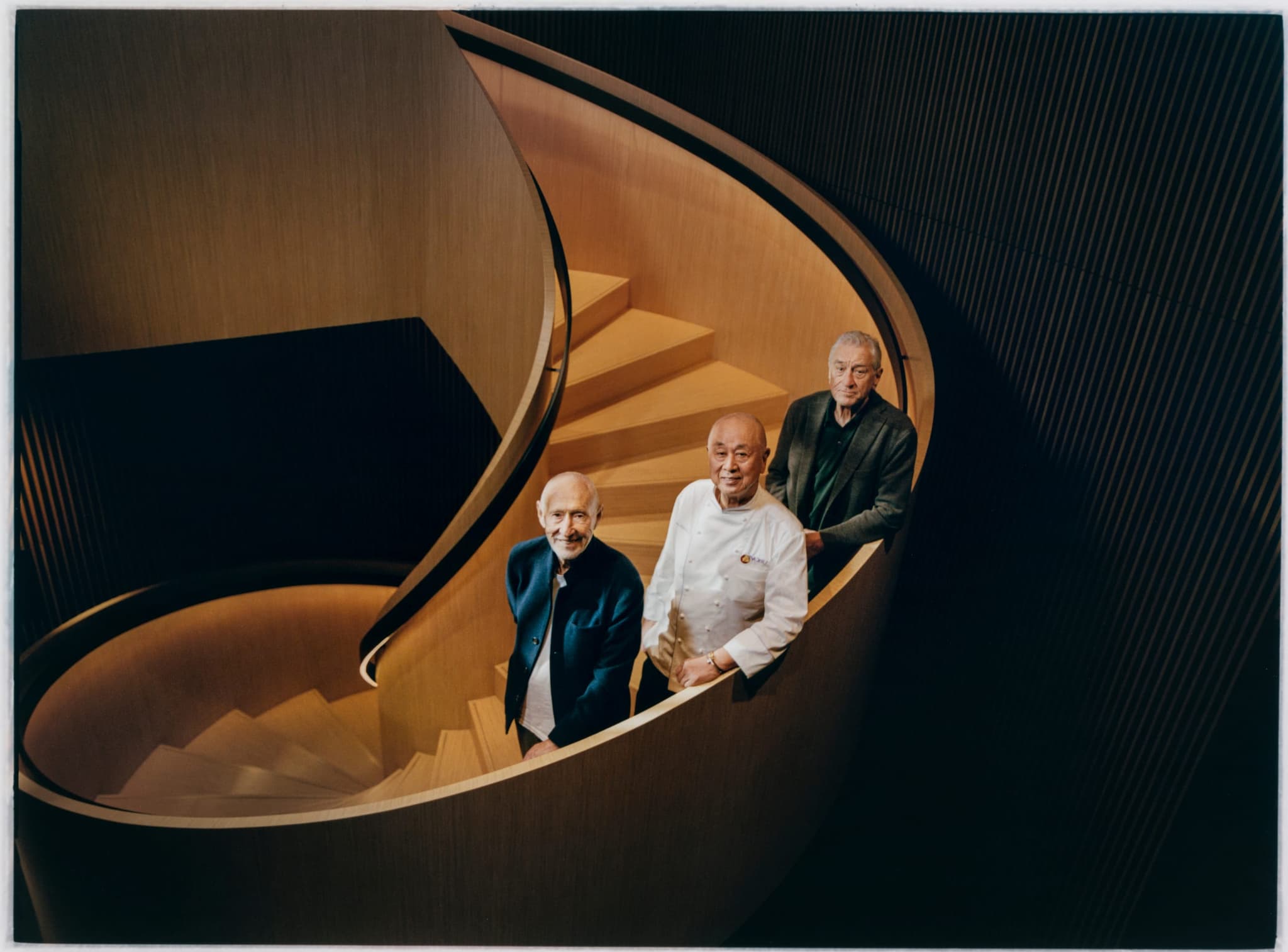 Spiral golden staircase at Nobu Hotel Warsaw with a group of people gathered below.