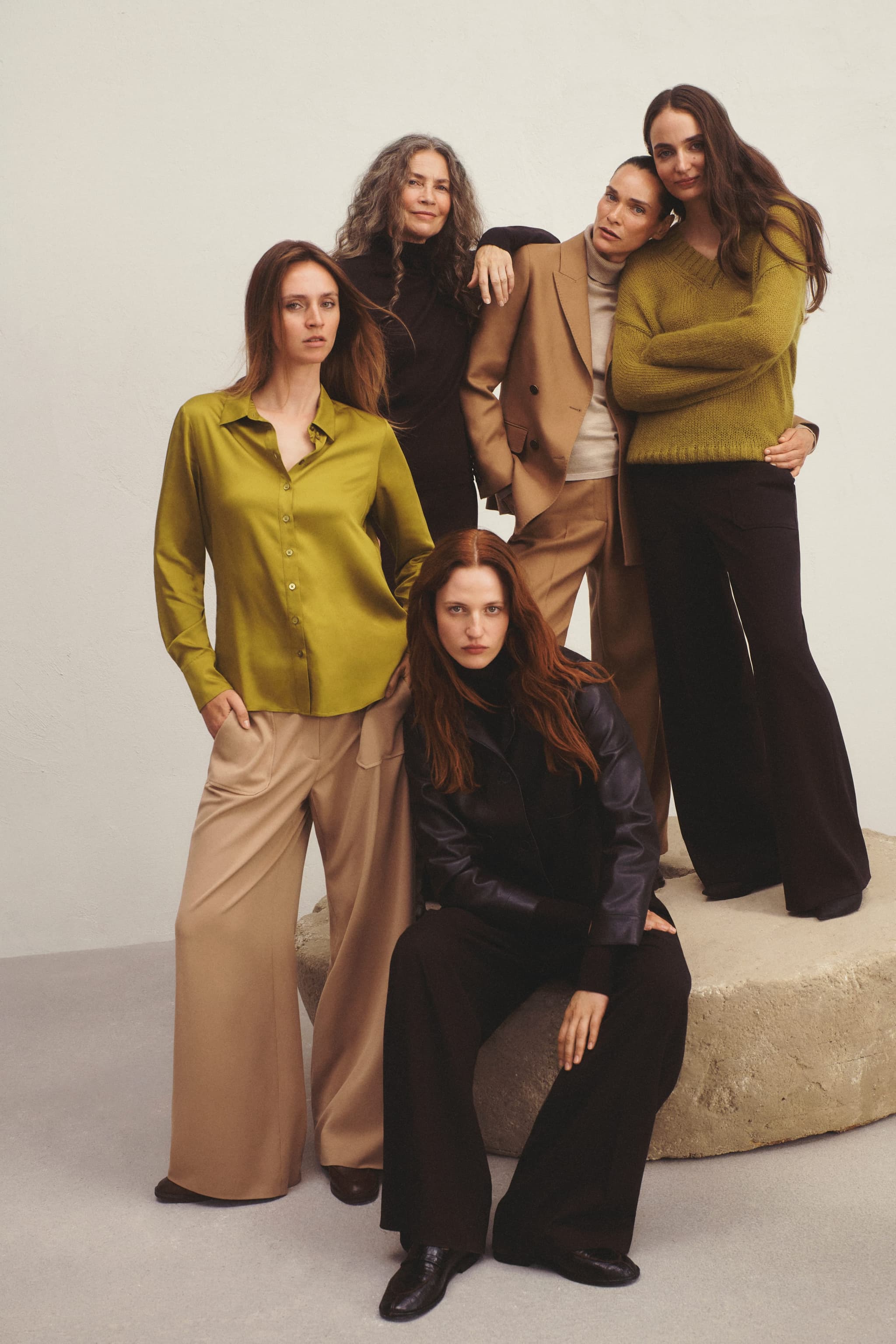 Group of women posing in tailored Tatuum outfits in olive, tan and black.